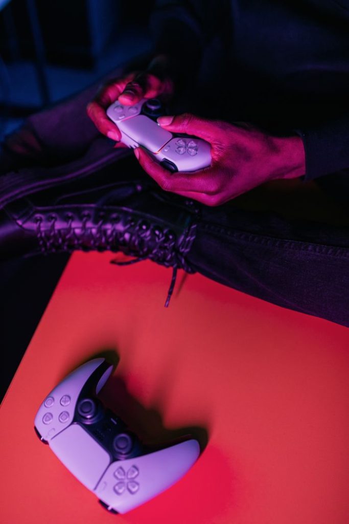 Close-up of a person holding a wireless game controller under vibrant lighting.