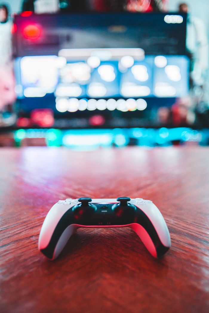 Crafting Captivating Headlines: Your awesome post title goes here A close-up of a gaming controller on a wooden table with vibrant screen in the background.